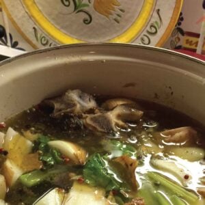 A pot of vegetables and bones cooking in a pot to make beef bone broth.