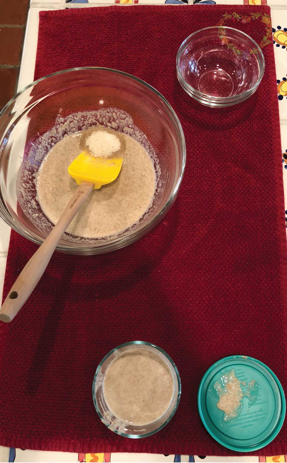 Making sourdough starter in a bowl with a spatula.