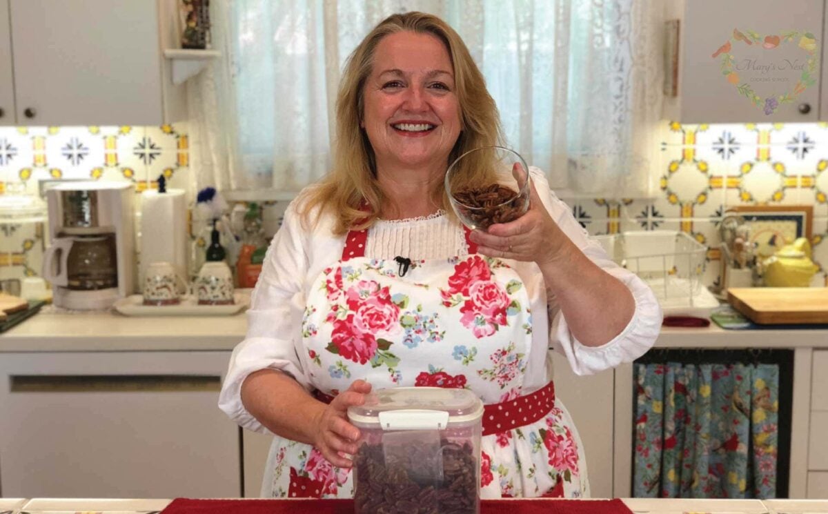 Mary in her kitchen with a container of soaked nuts on the counter in front of her.