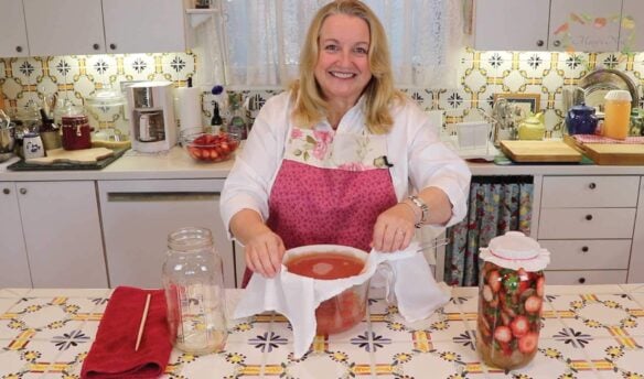 Mary in her kitchen making fruit scrap vinegar with strawberry tops in a bowl.