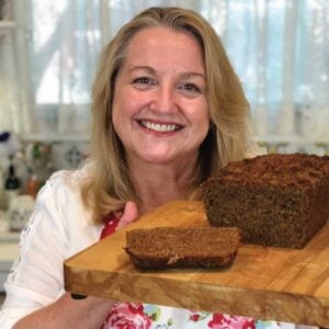 Mary holding cutting board with Cinnamon Crunch Banana Bread baked with Sprouted Flour.