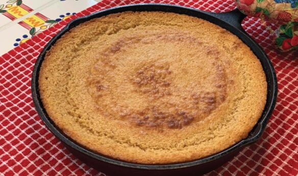 Whole grain cornbread cooked in a skillet on the table.