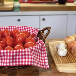 A basket of tomatoes, garlic, and onions on the table to make fresh tomato sauce.