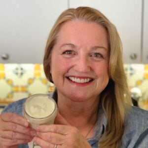 Mary holding up a jar of tallow balm after whipping and preparing for storage.