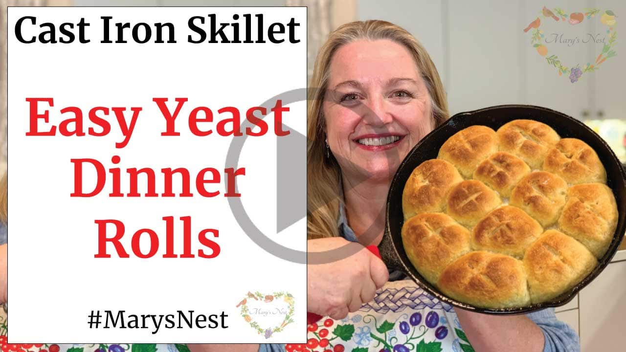 A youtube thumbnail with an image of Mary holding up a cast iron skillet with rolls in it and text on the left side.