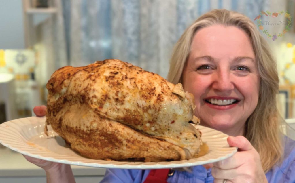 Mary holding a cooked turkey fresh from the Instant Pot.