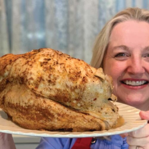 Mary holding a cooked turkey fresh from the Instant Pot.