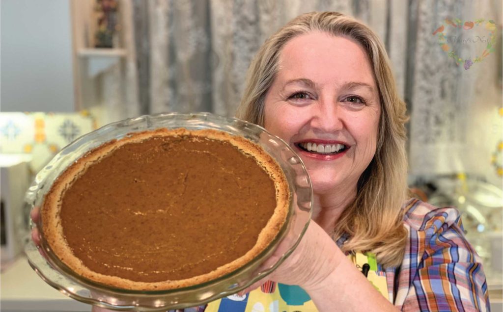 Mary holding a baked pumpkin pie.