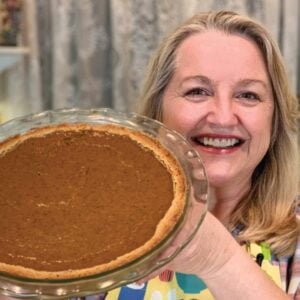 Mary holding a baked pumpkin pie.