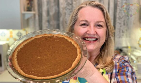 Mary holding a baked pumpkin pie.