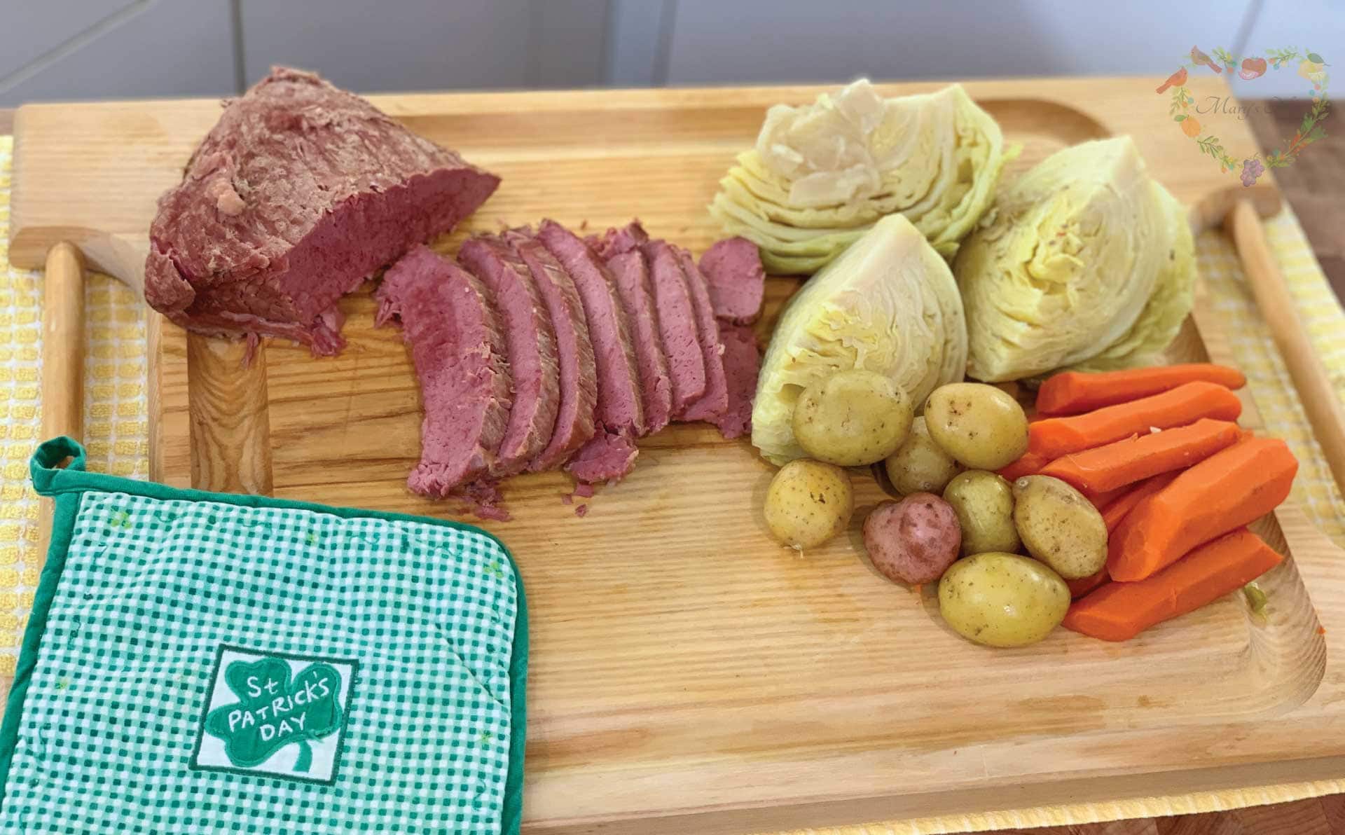 Corned Beef, Cabbage, Potatoes, and carrots on a tray with a St Patricks Day potholder.