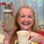 Mary holding jars with hot cocoa mix and a mug with hot chocolate.