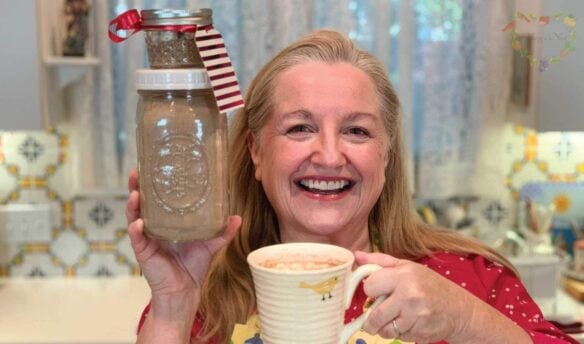 Mary holding jars with hot cocoa mix and a mug with hot chocolate.
