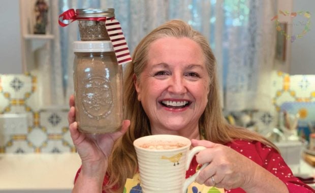 Mary holding jars with hot cocoa mix and a mug with hot chocolate.