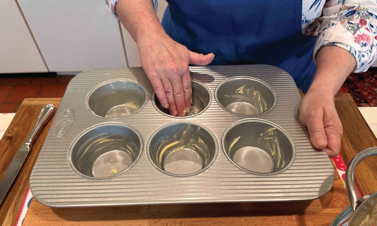 Mary showing how to butter a muffin tin pan