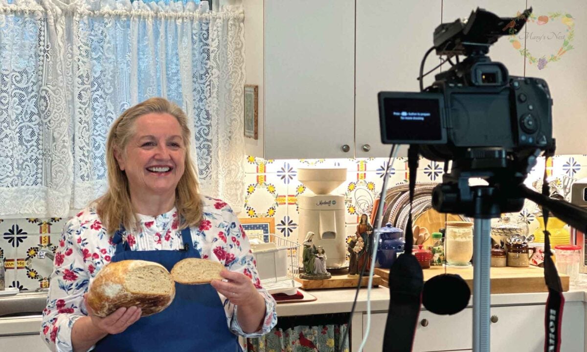 Mary holding sourdough bread in front of a camera.