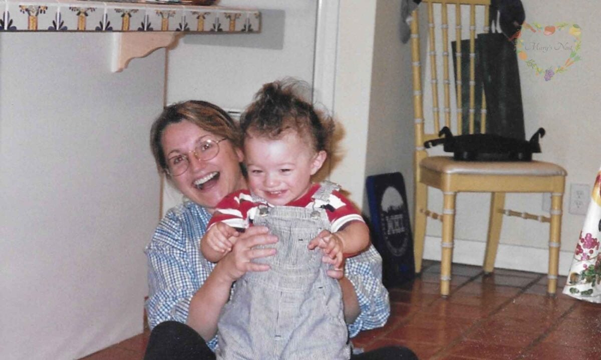 Mary holds her son in her kitchen.