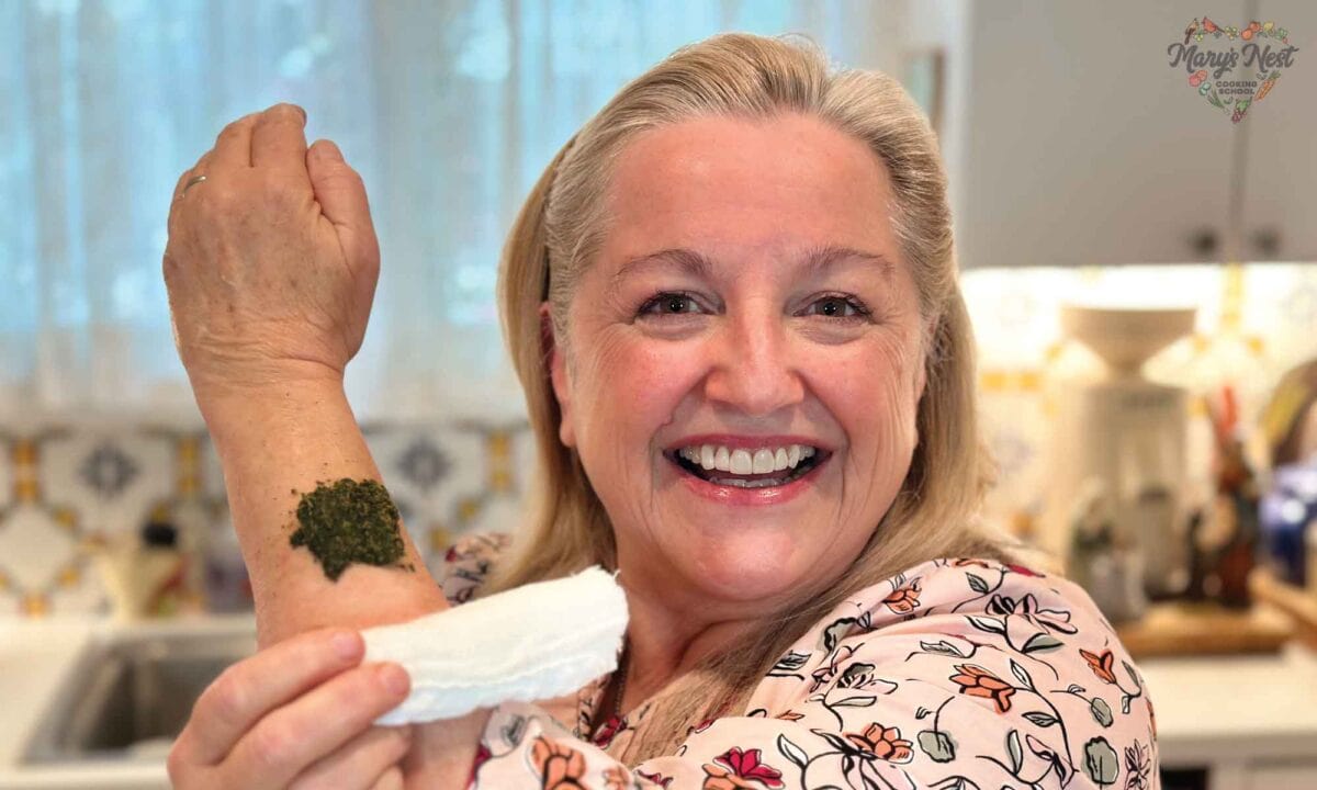 Showing the poultice on Mary's arm with her other hand holding a white bandage.